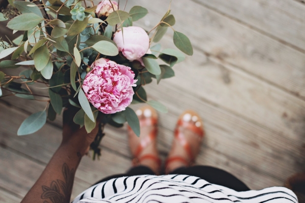 person holding pink flowers standing on pown wooden flooring