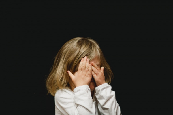 Little blonde hair girl covering her face with hands