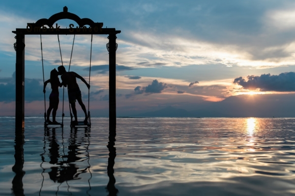 silhouette photography of couple standing on the sea while kissing