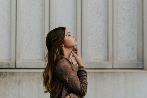 woman in pown long-sleeved top standing beside wall