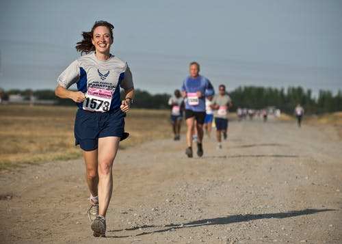 Woman in Gray Crew Neck Shirt Running on Brown Soil during Daytime