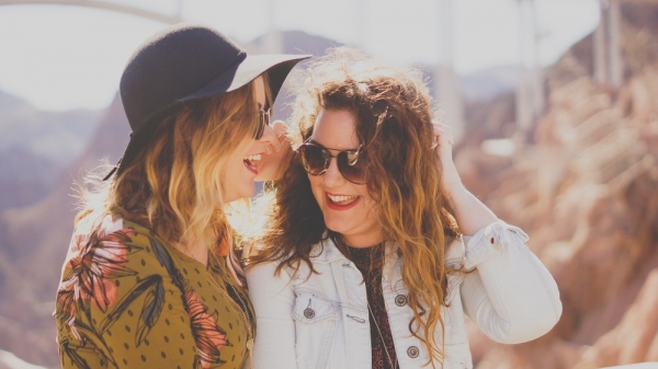 two women smiling while wearing sunglasses