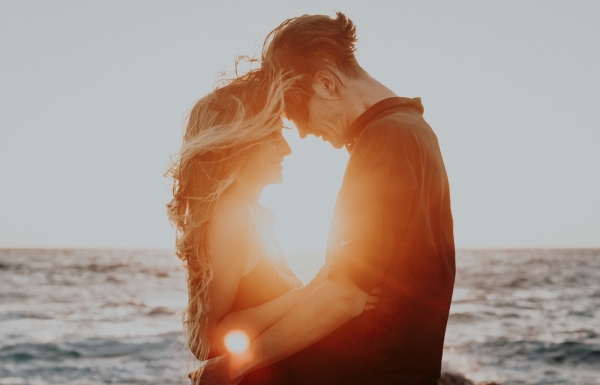 man and woman hugging near sea during golden hour