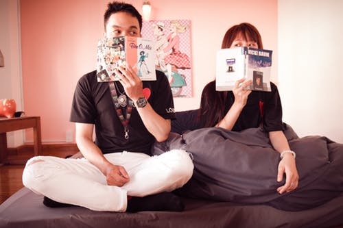 Couple Holding Books Sitting on Bed