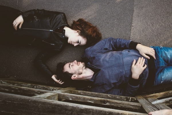 man and woman lying on gray concrete surface looking at each other