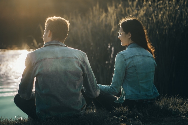 man and woman sitting near body of water